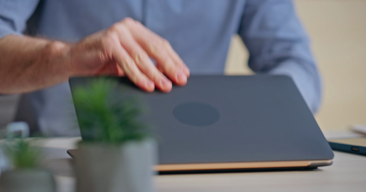 Businessman opening laptop at an office desk