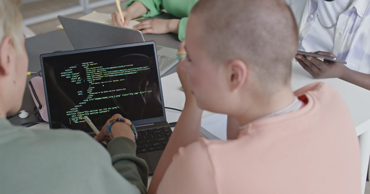 Two people reviewing code on a laptop screen together